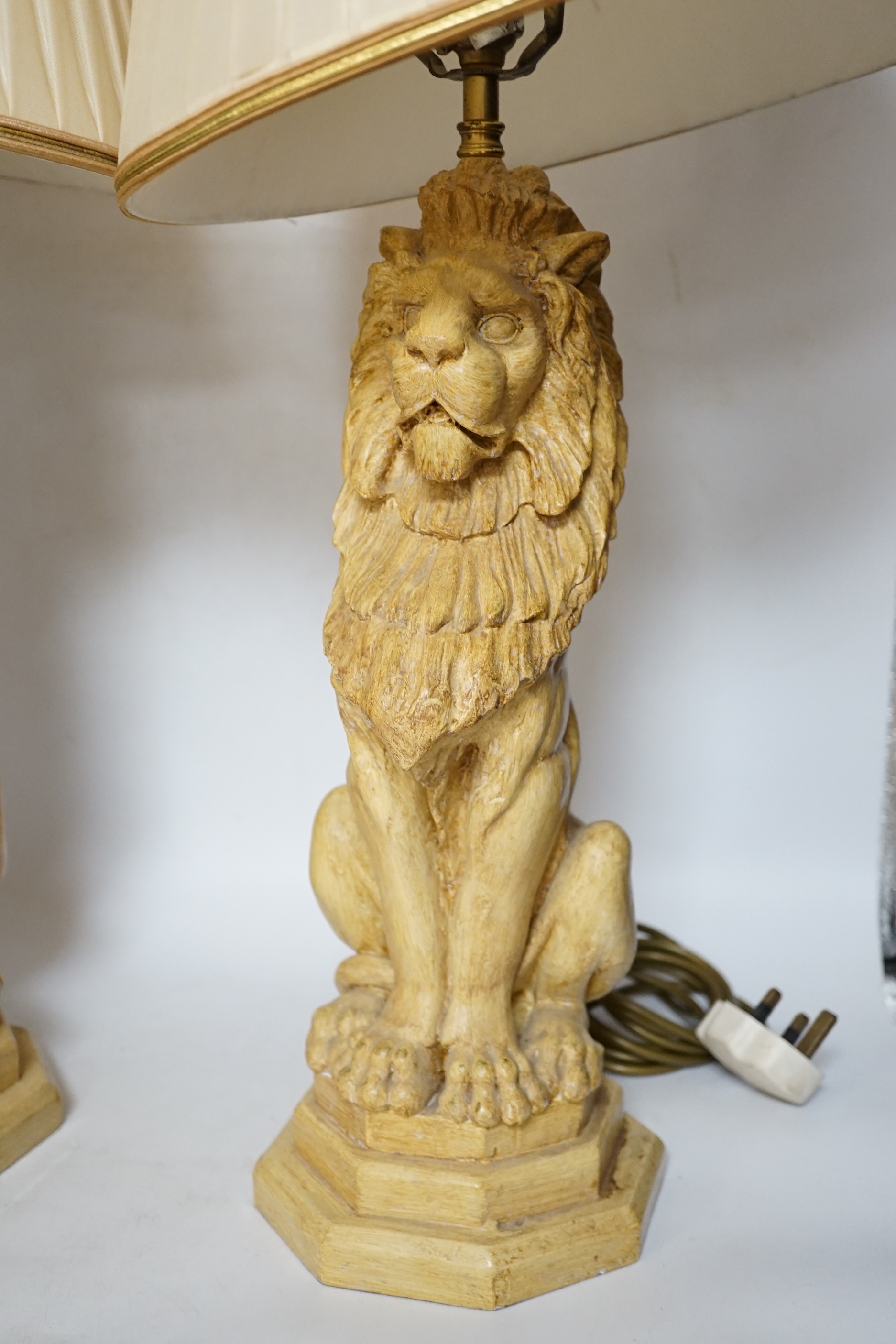 A pair of Thomas Blakemore composition lion lamps with cream shades, 64cm